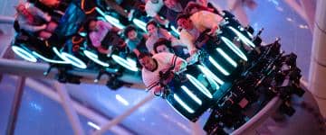 Riders react as they emerge outside during the initial launch of Tron Lightcycle Run