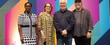 All four panelists stand in front of IAAPA branded backdrop.