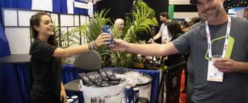 Woman at White Claw booth hands man a drink.