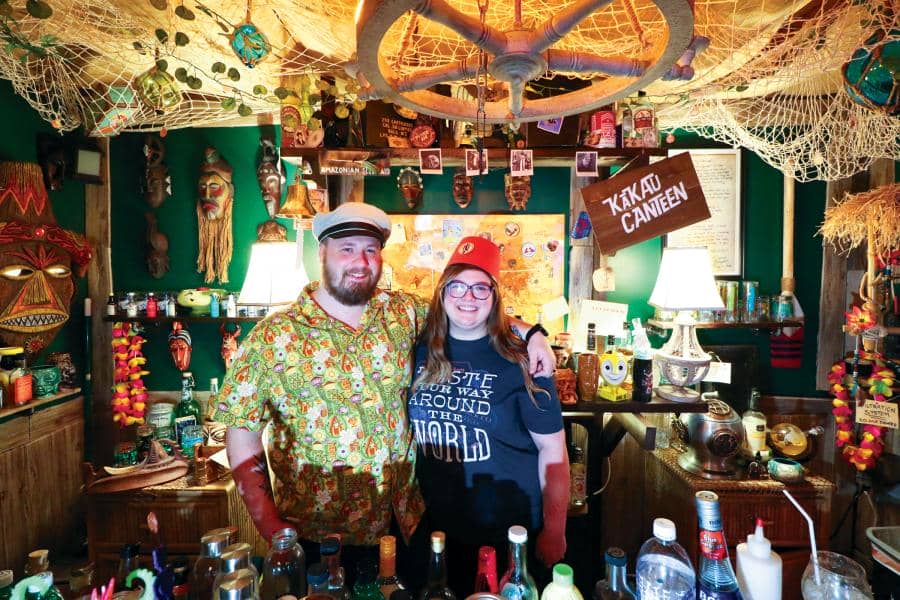 Jordan Hill and his wife, Sarah Hill, posing at the Kakau Canteen tiki bar that Jordan created from scratch