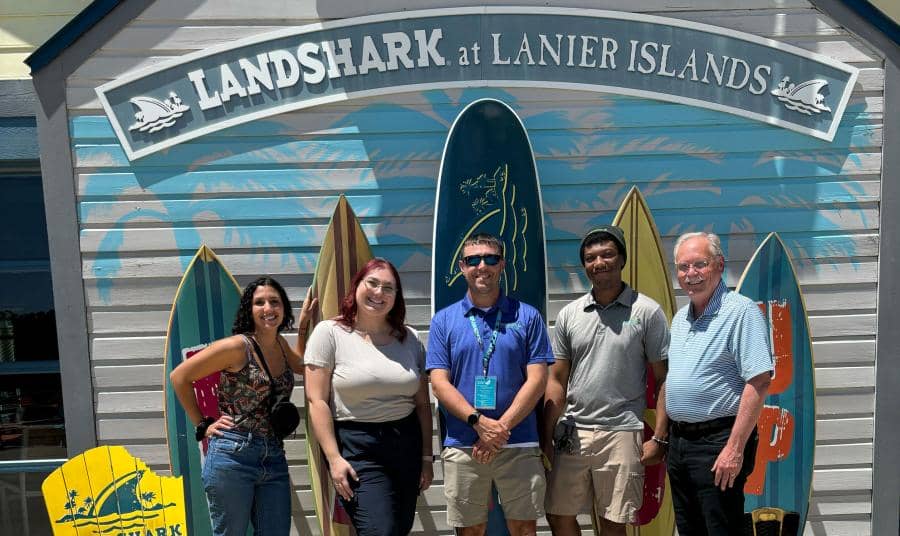 Margaritaville Lanier Islands employees smiling and posing for a picture, with LandShark Landing attraction decor in the background