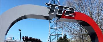 Top Thrill 2 roller coaster entrance sign at Cedar Point, with the coaster vehicle in the background