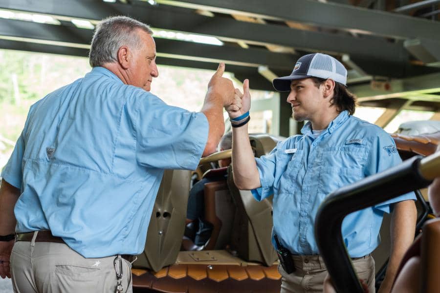 Two Silver Dollar City amusement park employees wearing their designated uniforms, fist-bumping with thumbs up 