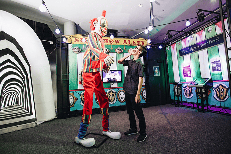 Clown stands over a child at the Phobia2 Exhibit 